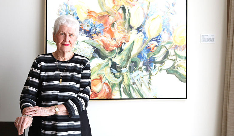 Westerleigh PARC resident Bette in front of floral painting