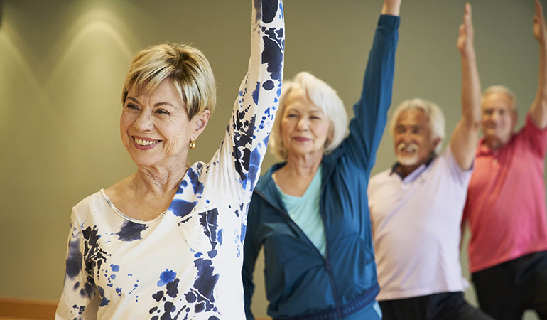 Residents with arms raised in a yoga class