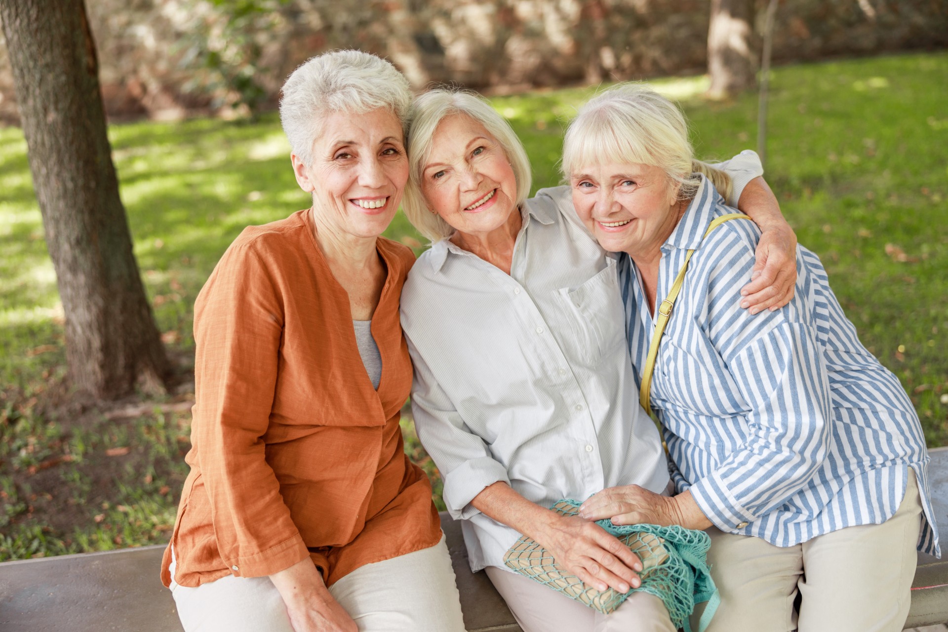 Three senior women happily holding each other
